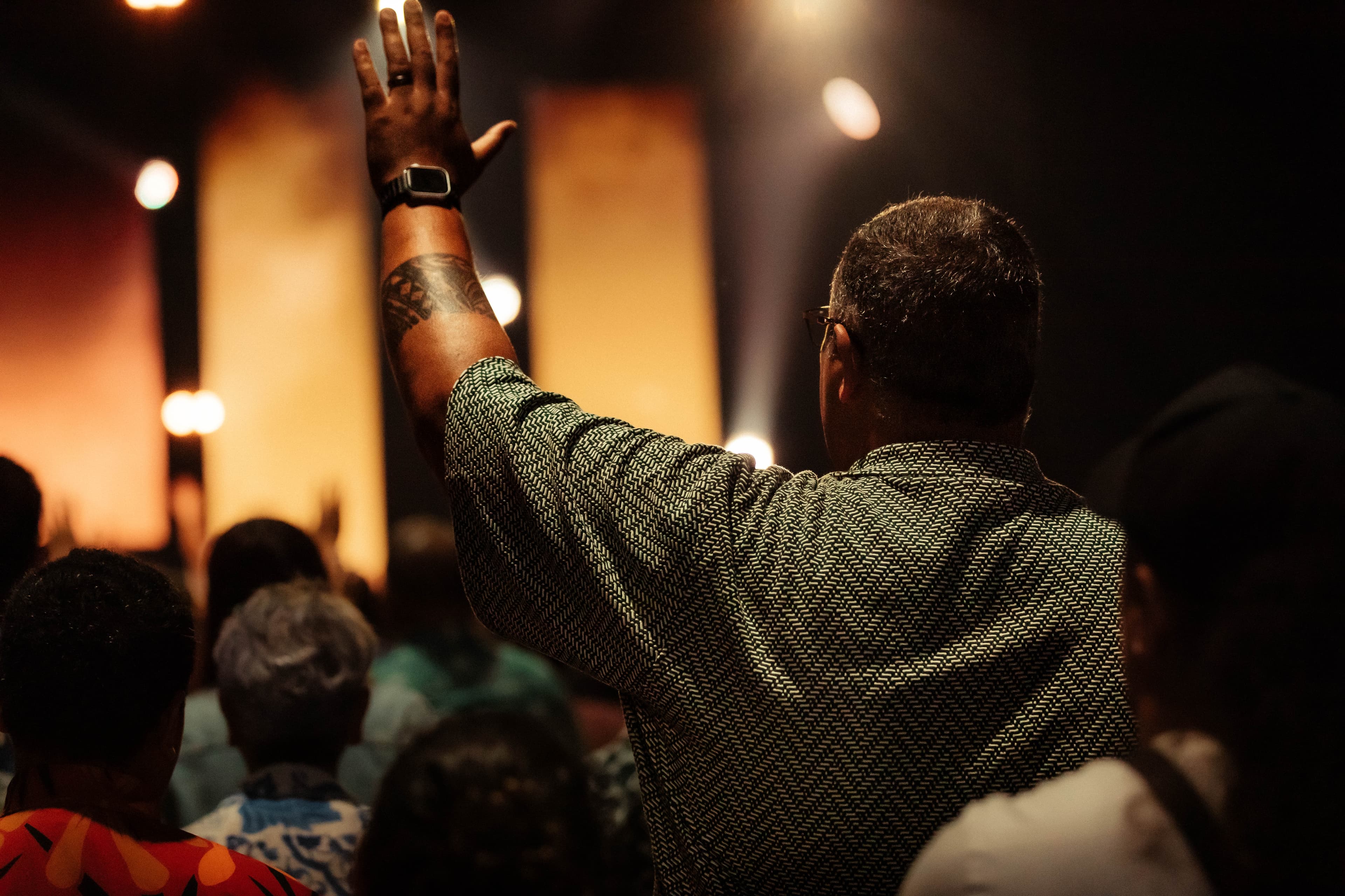 Man from behind with his hand raised in worship