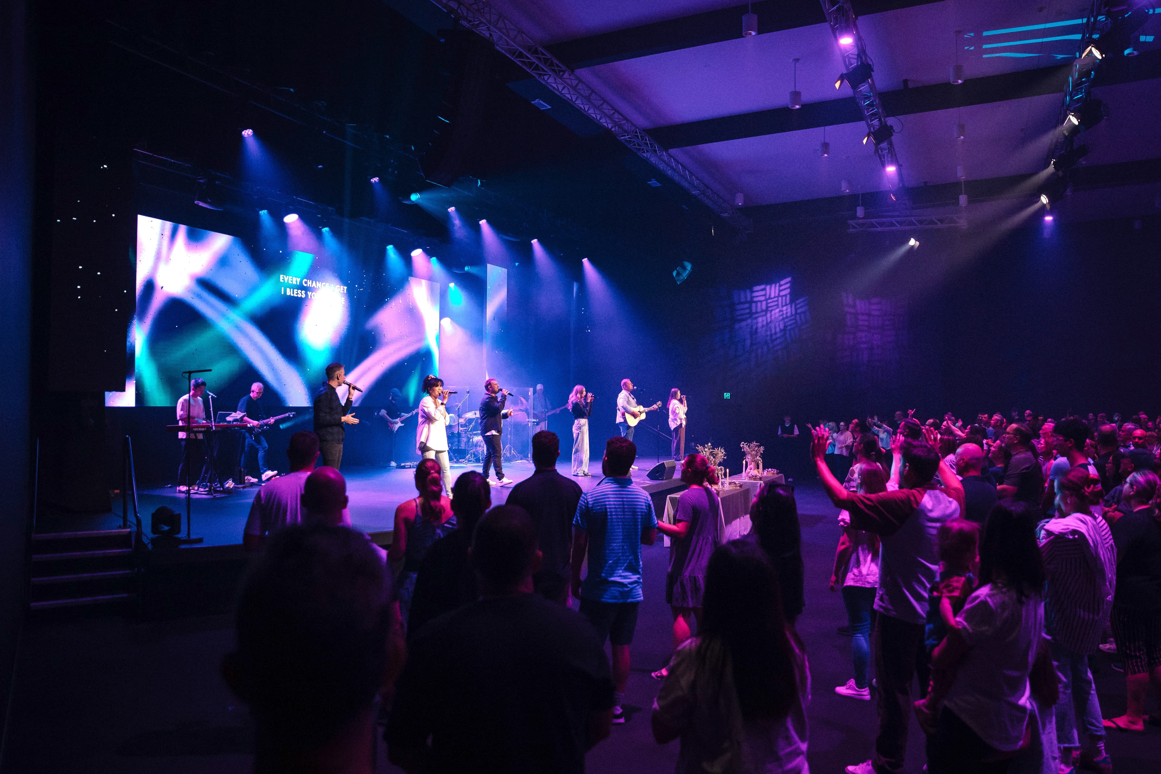 LIFE North from the left of the auditorium showing the stage and front of the congregation bathed in purple light