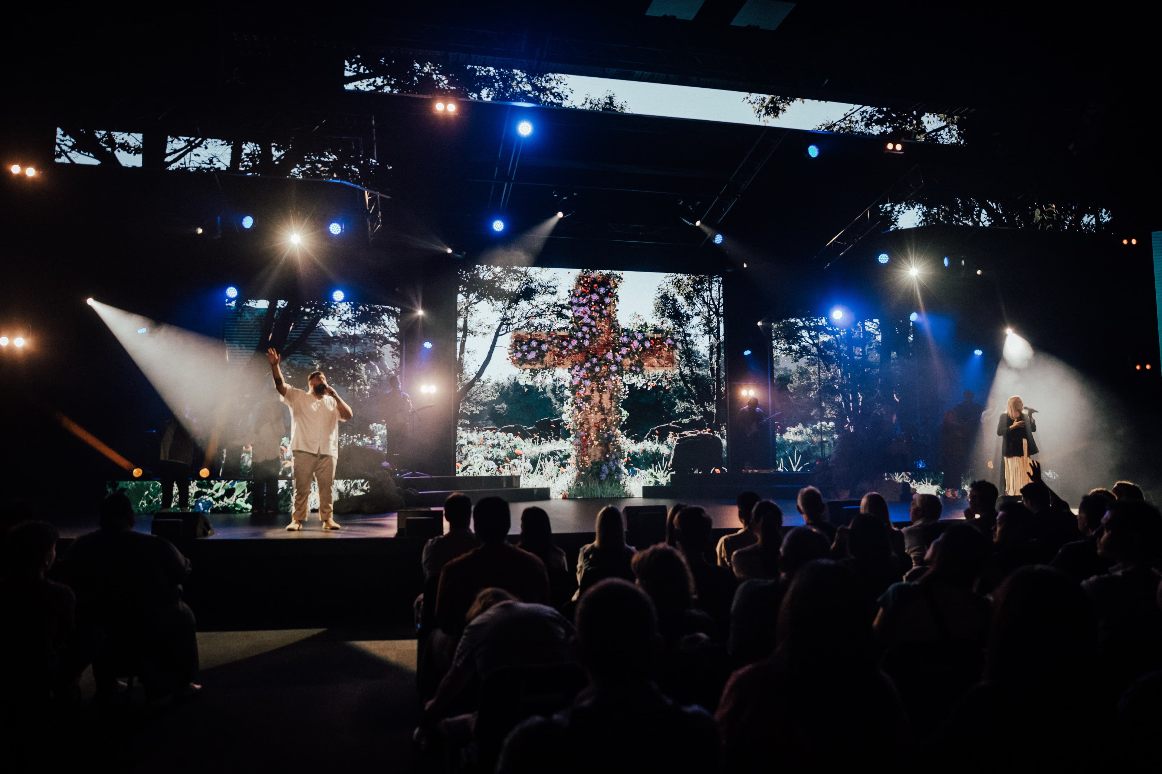 Good Friday service at Central campus with people singing on stage with large cross in the centre of the screen behind them