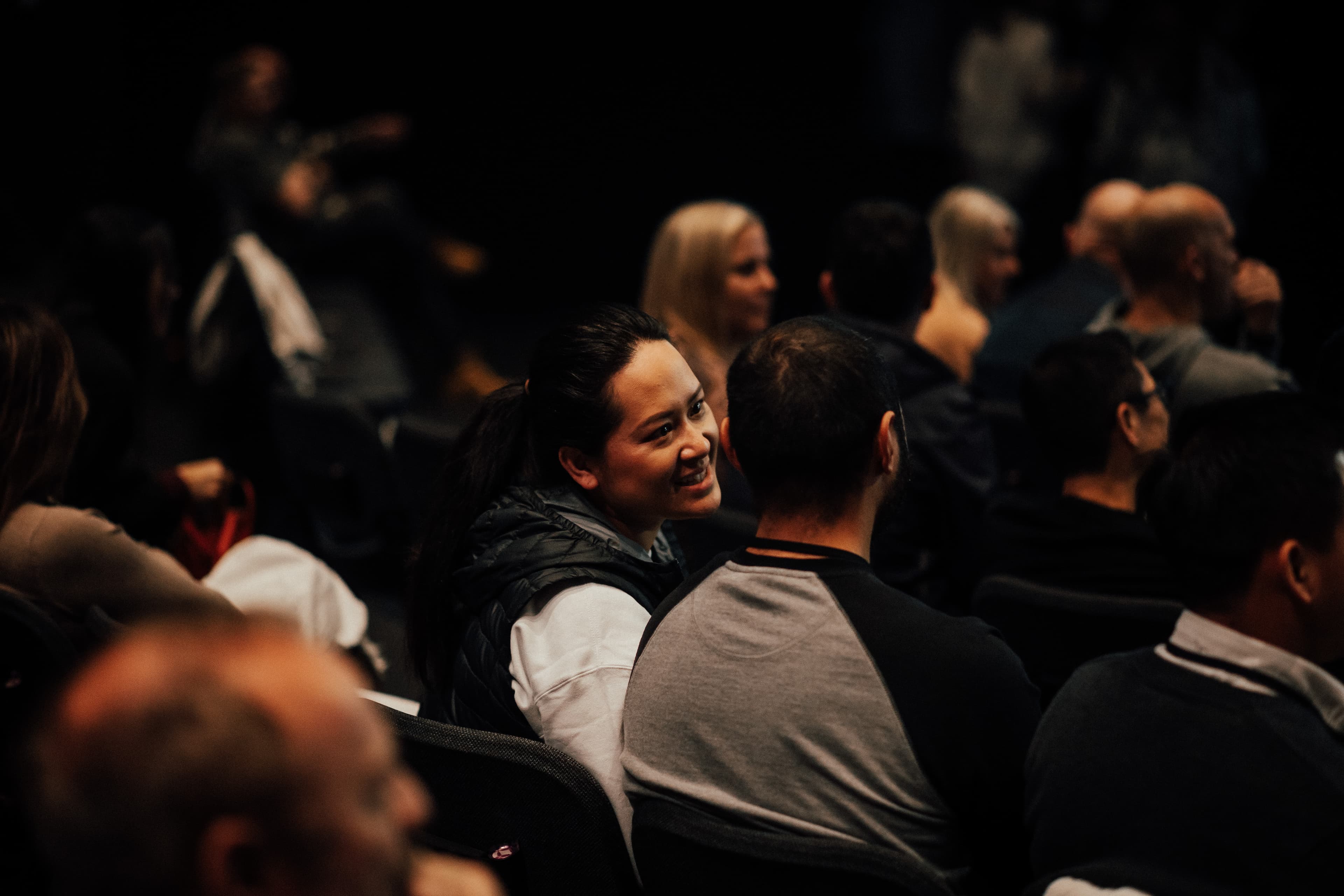 A couple sitting in the Auditorium at the Marriage Retreat at LIFE Central and the woman is looking lovingly at her husband