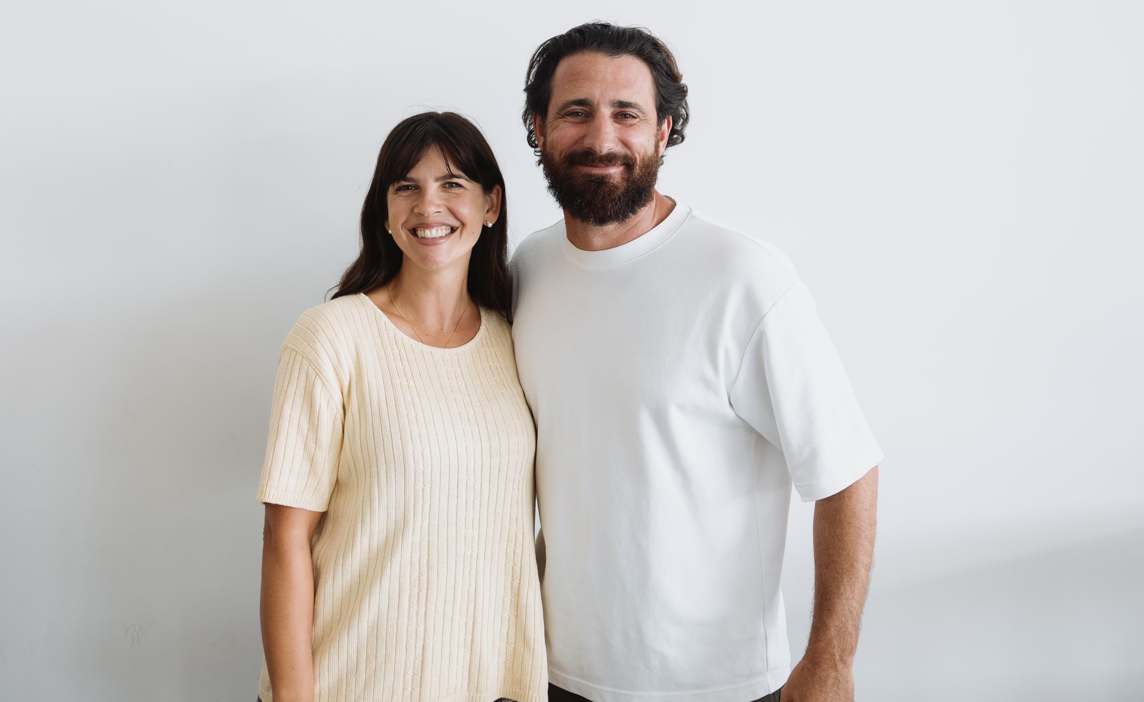Katie and Joel standing against a white background smiling at the camera