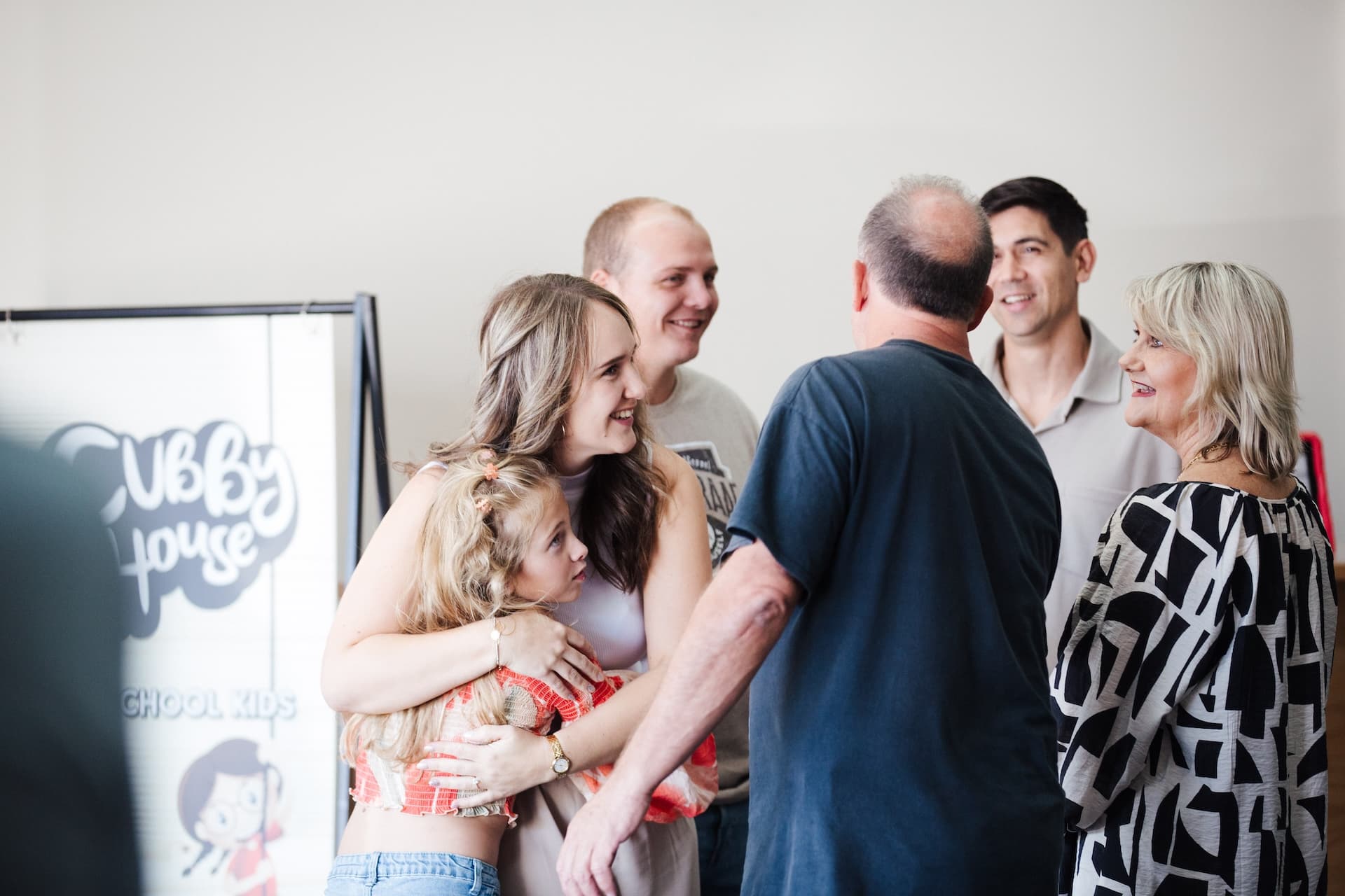 Woman and young girl standing in front of cubby house sign in the foyer