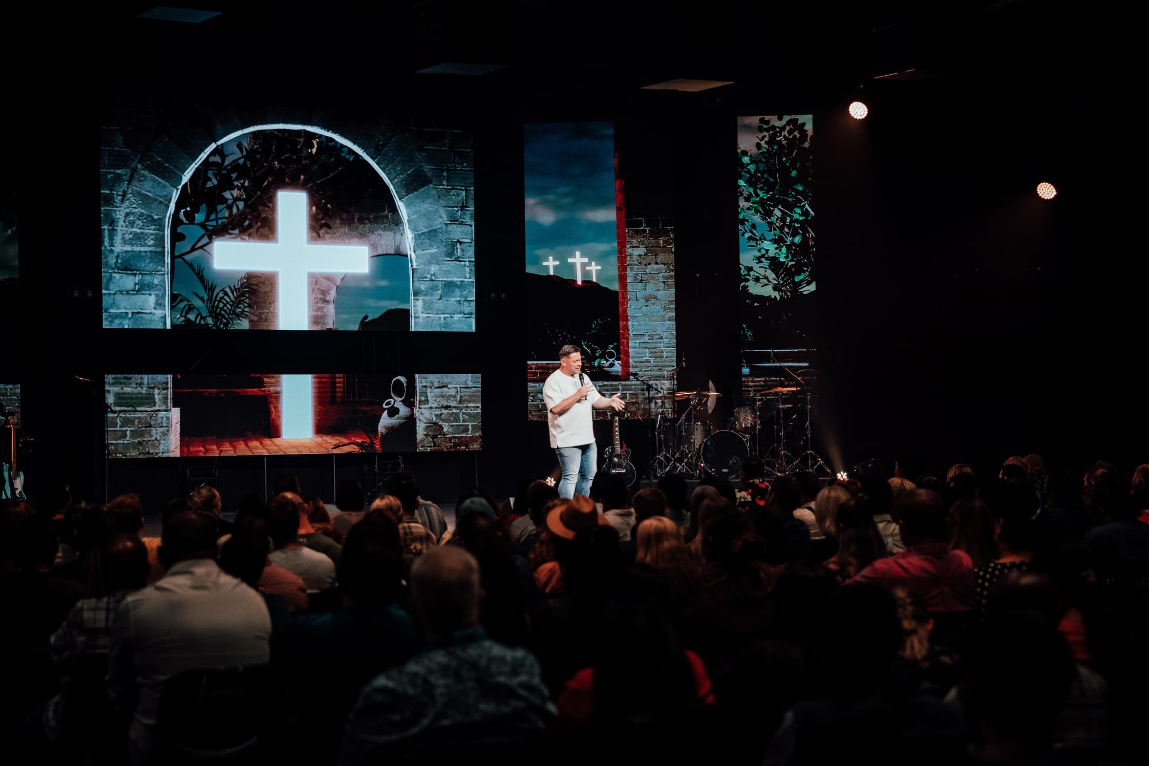 Preacher talking about the Resurrection with the cross displayed behind him