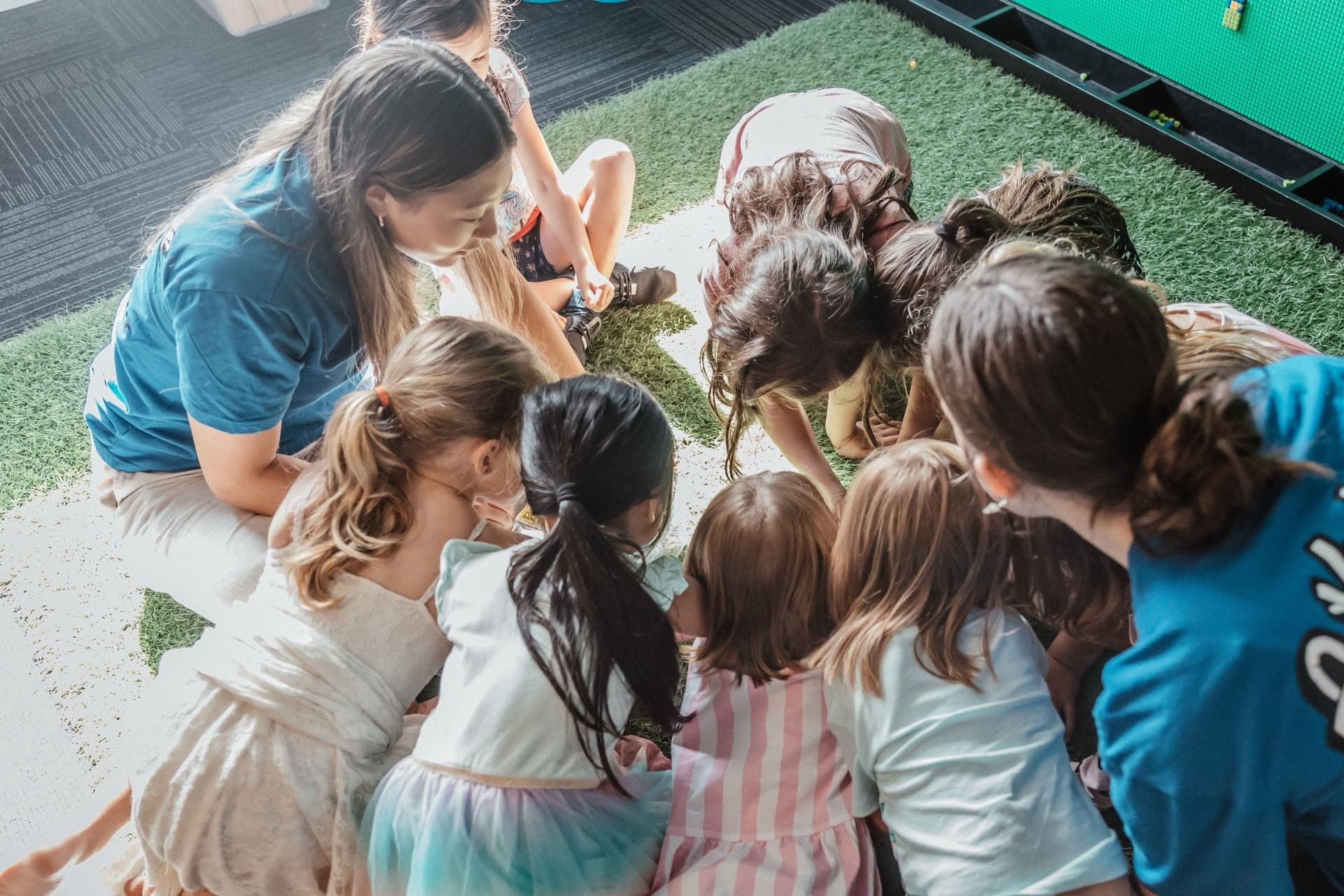 A group of kids looking at something, watched by the Adventure Kids leaders.