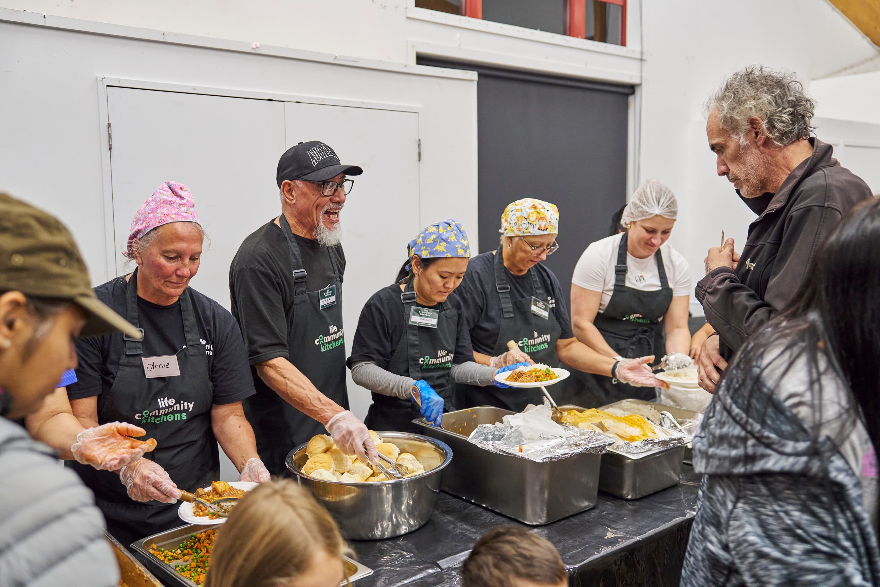 team of volunteers serving dinner to diners at LIFE Community Kitchens