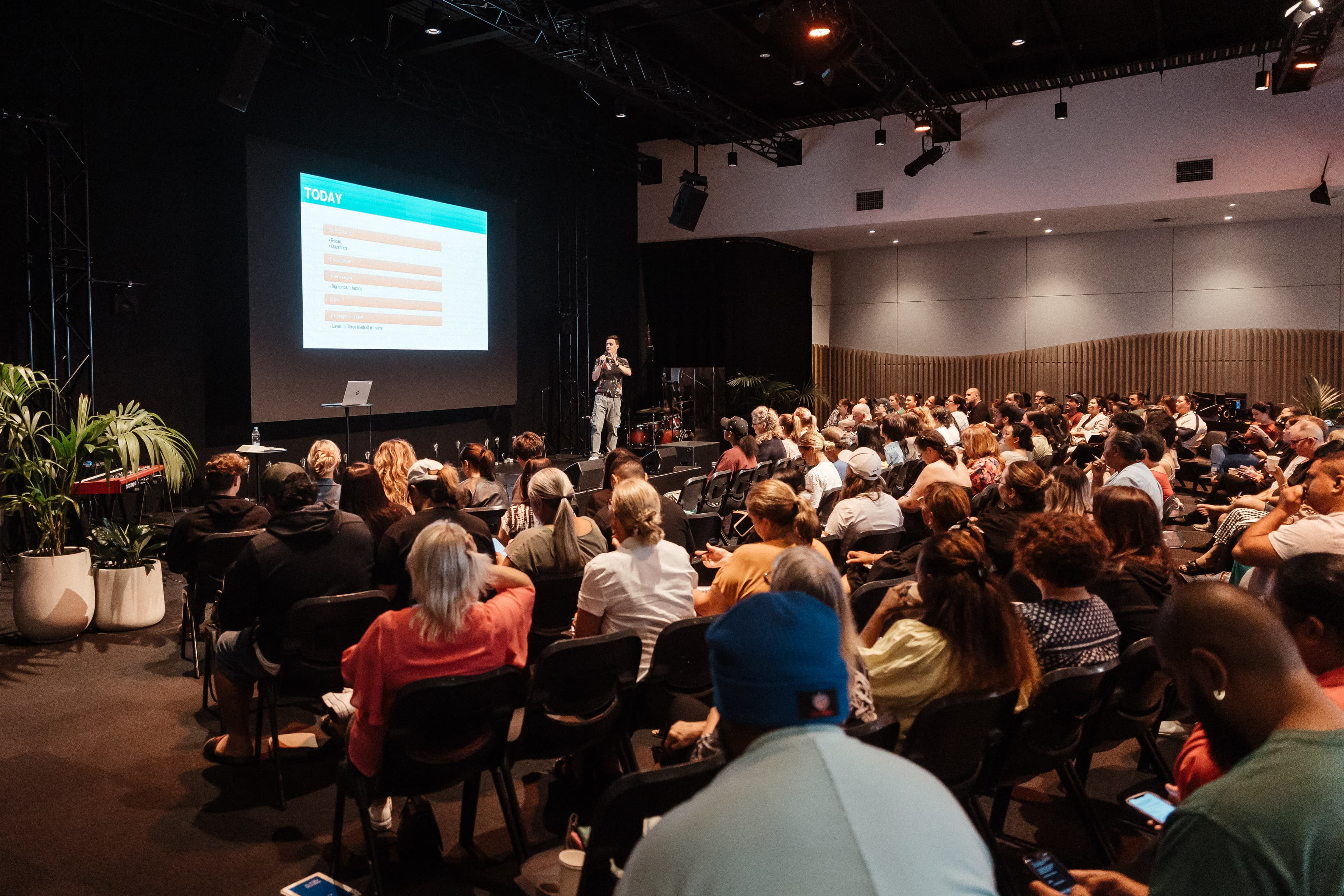 Wide shot of the Spiritual Formation course with the Chapel at Central Campus full of people listening to the facilitator who is standing on the stage with content on the screen behind him