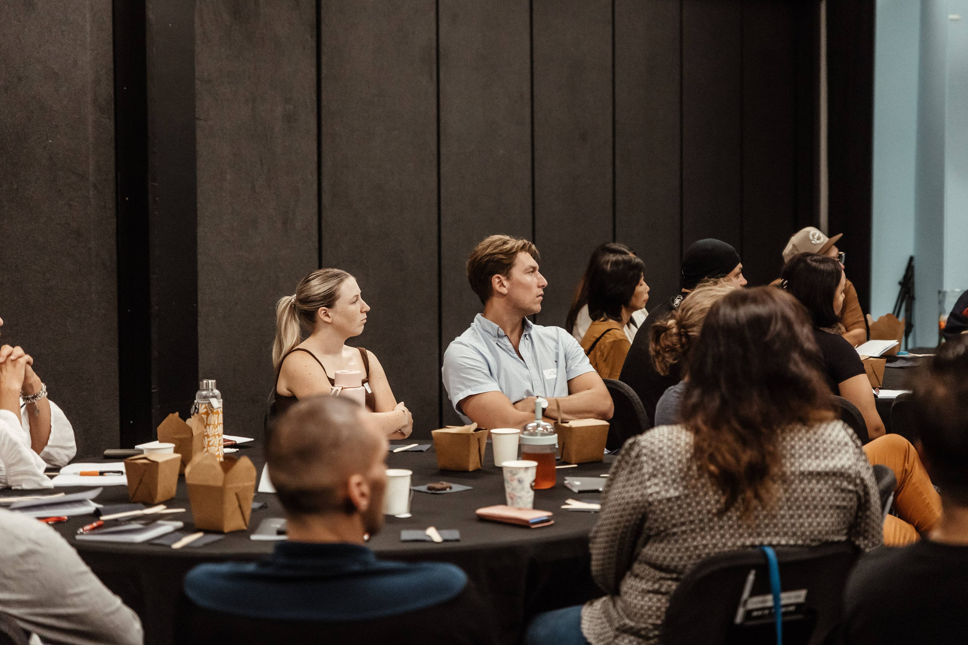 People listening to Alpha course material looking towards the stage with focus on a young man and woman