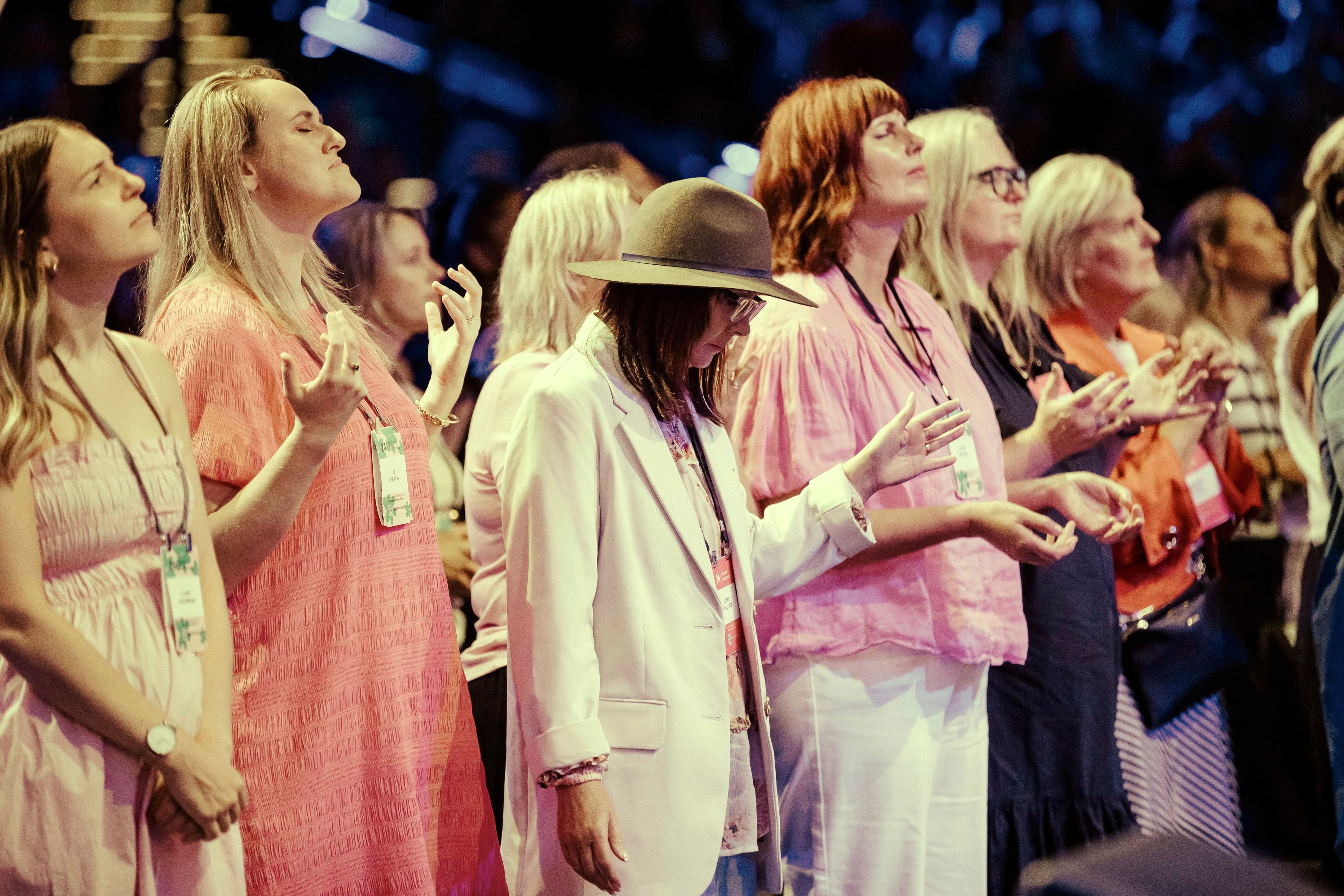 Women with their eyes closed and hands raised in prayer and worship